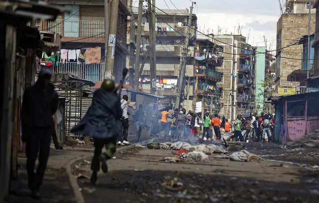 Kenyan riot police charge towards opposition protesters during clashes in the Mathare slum of Nairobi, Kenya Thursday, October 26, 2017. Opposition supporters boycotted Thursday's rerun of Kenya's disputed presidential election, clashing with police in some parts of the East African country and forcing authorities to postpone voting in areas affected by the violence. (Photo by Ben Curtis/AP Photo)