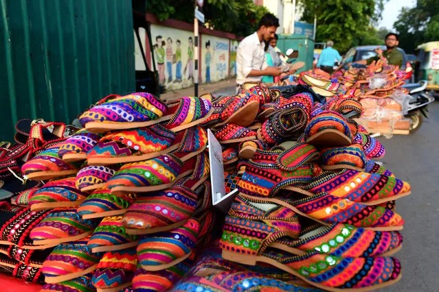 Vendors sell decorative traditional footwears along a street ahead of the Navratri festival in Ahmedabad on September 18, 2022. (Photo by Sam Panthaky/AFP Photo)