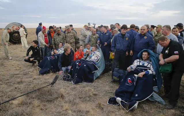 The crew of (L to R) Aidyn Aimbetov of Kazakhstan, Gennady Padalka of Russia and Andreas Mogensen of Denmark rest next to the capsule after landing near the town of Dzhezkazgan (Zhezkazgan), Kazakhstan, September 12, 2015. (Photo by Yuri Kochetkov/Reuters)