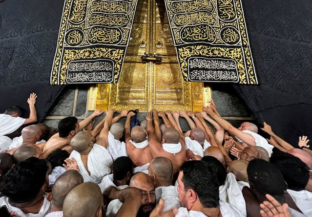 Muslims touch and pray at the door of the Kaaba during their Umrah, at the Grand Mosque, in the holy city of Mecca, Saudi Arabia on December 18, 2023. (Photo by Amr Abdallah Dalsh/Reuters)