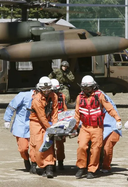 Firefighters carry a hiker from a helicopter after a rescue operation near the peak of Mt. Ontake in Kiso town, Nagano prefecture, central Japan in this September 28, 2014 photo taken and released by Kyodo. (Photo by Reuters/Kyodo News)