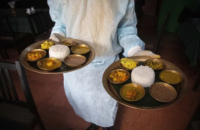 A waiter wearing personnel protection kit serves food in a restaurant in Gauhati, India, Wednesday, June 10, 2020. With thousands of cases reported daily now India stands the fifth highest in the world of coronavirus cases. There has also been a surge in infections in rural India following the return of hundreds of thousands of migrant workers who lost their jobs during the lockdown. (Photo by Anupam Nath/AP Photo)