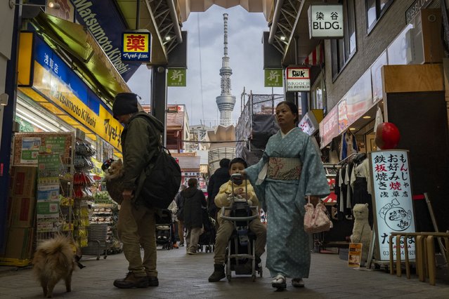 This picture taken on February 21, 2025 shows people walking past shops in the Asakusa area as the 634m-high (2,080 ft.) Tokyo Skytree (back C) is pictured in the distance in the Japanese capital. Originally planned to be 610 metres high, architects went even bigger and the Skytree was certified by Guinness World Records as the world's tallest tower when it opened in 2012. (Photo by Yuichi Yamazaki/AFP Photo)