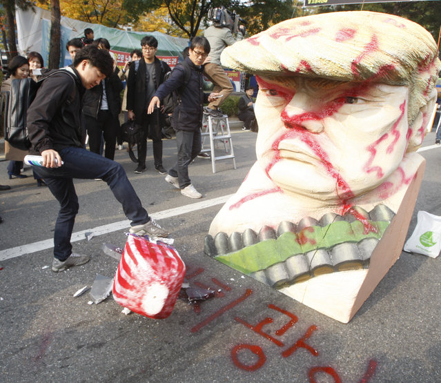 A South Korean protester kicks a mock rocket after spray painting the word “lunatic” next to a bust resembling US President Donald J. Trump during a rally held to show opposition to Trump's visit to South Korea, near the National Assembly in Seoul, South Korea, 08 November 2017. Trump is on a two-day official visit to South Korea, the second stop on his 12 day tour of Asia. (Photo by Kim Hee-Chul/EPA/EFE)