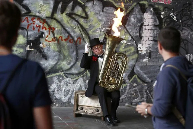 A street performer entertains tourists by playing his flame-throwing tuba on the South Bank in London, Britain August 20, 2016. (Photo by Peter Nicholls/Reuters)
