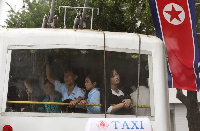 People ride on a trolley bus past a North Korean national flag flown to mark the celebration of the Songun Day or the “Military First” holiday in Pyongyang, North Korea, Thursday, August 25, 2016. North Korea marked its “Military First” holiday on Thursday with mass dancing, outdoor concerts and boasts of a successful – and potentially game-changing – submarine-launched ballistic missile test it hopes will serve as a warning to Washington and Seoul to stop holding joint military exercises Pyongyang sees as a dress rehearsal for invasion. (Photo by Dita Alangkara/AP Photo)