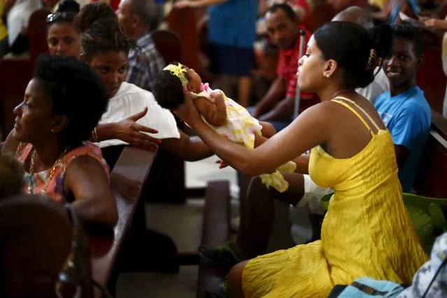 A parishioner holds a baby during a mass celebrating Pope Francis' visit, in the church of the Virgin of Charity of El Cobre in Havana, September 18, 2015. (Photo by Edgard Garrido/Reuters)