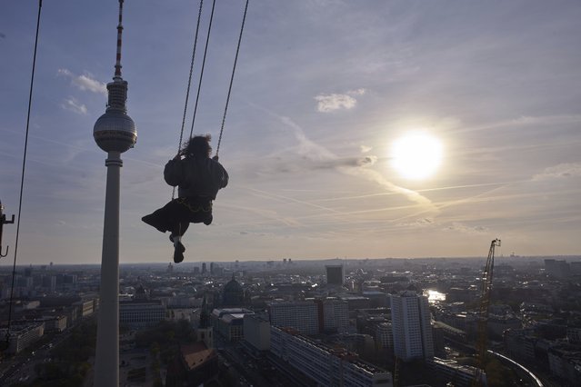 A woman swings on the High Swing Berlin at Alexanderplatz on a sunny spring evening, in Berlin, Germany, Thursday, April 10, 2025. (Photo by Markus Schreiber/AP Photo)