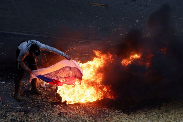 A farmer burns a Russian flag during a protest of European farmers over price pressures, taxes and green regulation, on the day of an EU Agriculture Ministers meeting in Brussels, Belgium on February 26, 2024. (Photo by Yves Herman/Reuters)