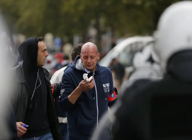 An injured  plain-clothes policeman is assisted during clashes at a march against government reforms and cost-cutting measures in Brussels , October 7, 2015. (Photo by Francois Lenoir/Reuters)