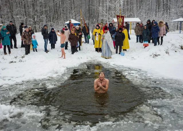 A man takes a dip in icy water during Orthodox Epiphany celebrations in the village of Ivankovychi, Ukraine on January 19, 2018. (Photo by Gleb Garanich/Reuters)