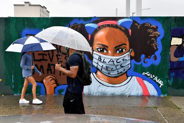 People carrying umbrellas walk by a BLM mural on 4th Avenue and Union Street as Tropical storm Fay hits NYC on July 10, 2020. (Photo by Paul Martinka/The New York Post)