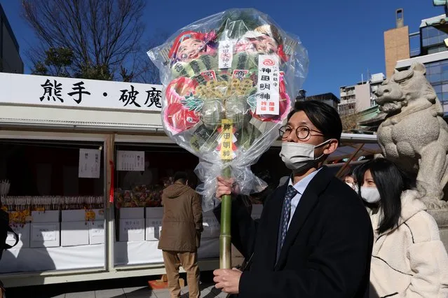 A man carries a Kumade (a bamboo rake decorated with good luck charms) at Kanda Myojin Shrine on January 04, 2023 in Tokyo, Japan. Kanda Myojin Shrine is located near several business districts in Tokyo and many people visit the shrine on the first day of work to pray for thriving business for a new year. (Photo by Takashi Aoyama/Getty Images)