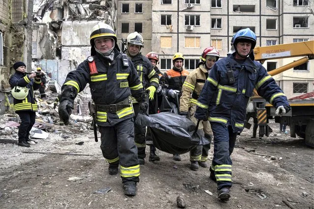 Rescue workers carry the body of a man who was killed in a Russian missile strike on an apartment building in the southeastern city of Dnipro, Ukraine, Monday, January 16, 2023. (Photo by Evgeniy Maloletka/AP Photo)