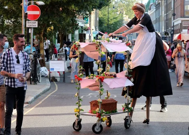 A performer on stilts interacts with a member of the public during the annual Bermondsey Street Festival in London, England, Saturday, September 19, 2020. (Photo by Tony Hicks/AP Photo)