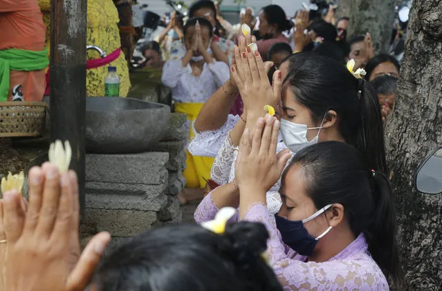 Women wearing face masks as a precaution against the new coronavirus outbreak pray during a Hindu ritual prayer at a temple in Bali, Indonesia, Wednesday, September 16, 2020. (Photo by Firdia Lisnawati/AP Photo)