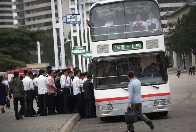 North Koreans board a bus during morning rush hour on Wednesday, September 28, 2016, in Pyongyang, North Korea. Rush hour generally hits its peak at about seven in the morning. Pedestrians hustle along the sidewalks or peddle along on the city’s bike lanes, usually narrow strips of sidewalk painted green that started to appear about a year ago, while workers and students who can’t walk or bike to where they need to go load onto the subways and fill the city’s buses and electric streetcars. (Photo by Wong Maye-E/AP Photo)