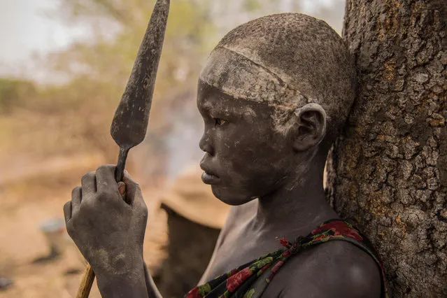 A Sudanese boy from Dinka tribe holds his spear at their cattle camp in Mingkaman, Lakes State, South Sudan on March 3, 2018. (Photo by Stefanie Glinski/AFP Photo)