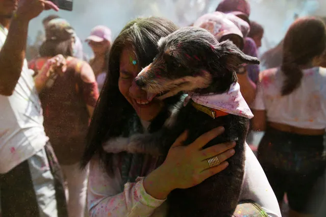 A woman carries her dog during a symbolic Holi celebration organized by the Embassy of India, in San Salvador, El Salvador on March 4, 2023. (Photo by Jose Cabezas/Reuters)