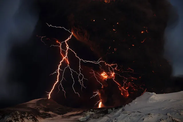 Lightning streaks across the sky as lava flows from a volcano in Eyjafjallajokul, Iceland, April 17, 2010. (Photo by Lucas Jackson/Reuters)