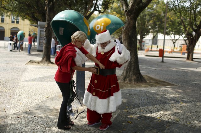 A woman helps a student of the "Escola de Papai Noel do Brasil" (Brazil's school of Santa Claus) to adjust his clothes before he boarded a ferry to attend the graduation ceremony, in Rio de Janeiro, Brazil, November 10, 2015. (Photo by Pilar Olivares/Reuters)