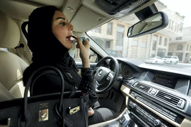 Enaam Gazi al-Aswad, 43, one of the first female drivers hired by the ride sharing company Careem but waiting for Saudi license to be issued by the government, applies lipstick inside her car at a company's office in Jeddah, Saudi Arabia on June 24, 2018. (Photo by Zohra Bensemra/Reuters)