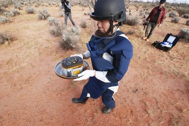 In this photo provided by the Japan Aerospace Exploration Agency (JAXA), a member of JAXA retrieves a capsule dropped by Hayabusa2 in Woomera, southern Australia, Sunday, December 6, 2020. A Japanese capsule carrying the first samples of asteroid subsurface shot across the night atmosphere early Sunday before successfully landing in the remote Australian Outback, completing a mission to provide clues to the origin of the solar system and life on Earth. (Photo by JAXA via AP Photo)