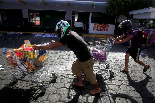People with goods looted from a store push shopping trolleys along a street after protests over a reform to the pension plans of the Nicaraguan Social Security Institute (INSS) in Managua, Nicaragua, April 22, 2018. (Photo by Jorge Cabrera/Reuters)