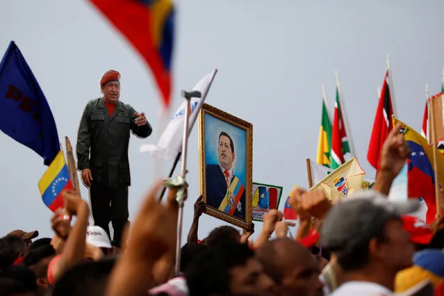 Supporters of Venezuela's President Nicolas Maduro holding a cardboard cut-out and a painting depicting Venezuela's late President Hugo Chavez attend a campaign rally in La Guaira, Venezuela May 2, 2018. (Photo by Carlos Garcia Rawlins/Reuters)