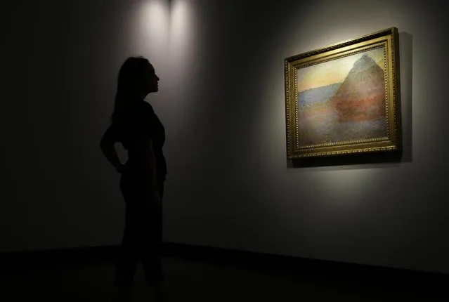A member of staff poses for the media next to a work of art by Claud Mont entitled “Merle” (Granistack), 1891, at Christie's auction house in London, Monday, October 24, 2016. The painting is to be sold in New York on Nov. 16, with an estimated value of 45 million pounds (55 million US$). (Photo by Alastair Grant/AP Photo)