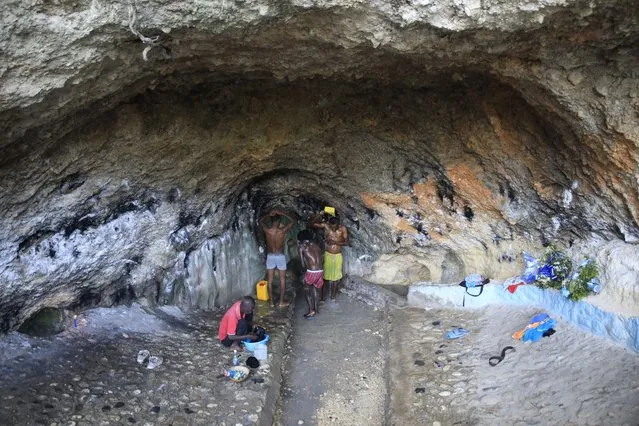 People bathe and do their laundry in a spring inside a cave due to no running water at their home in Port-au-Prince, Haiti, Tuesday, March 21, 2023. (Photo by Odelyn Joseph/AP Photo)