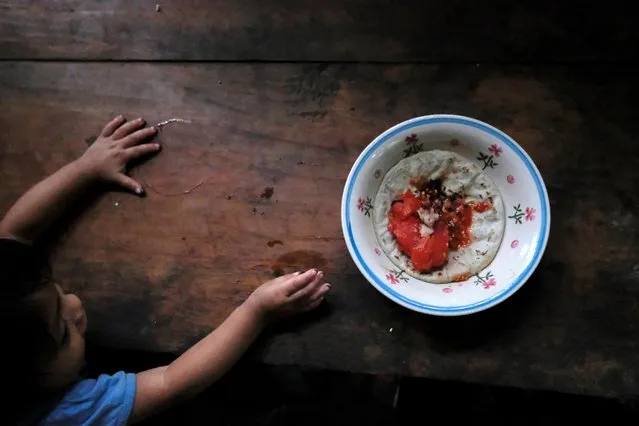 Carlos, a 22-months old boy, reaches for a plate with a tortilla with salt and a cooked tomato, at his home, in La Palmilla, Guatemala on October 9, 2020. (Photo by Josue Decavele/Reuters)