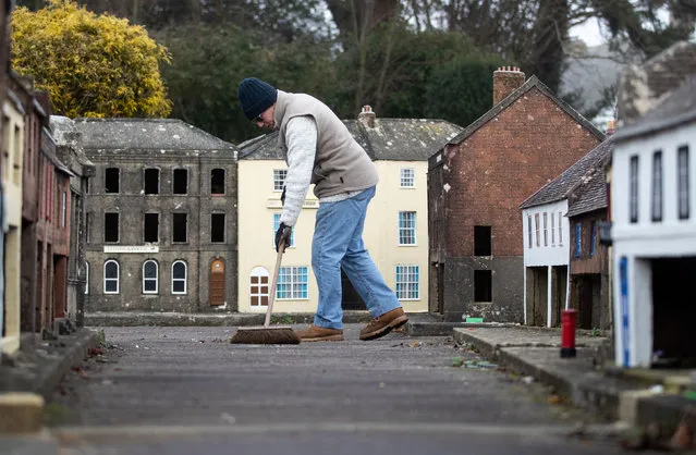 A volunteer sweeps a street at the Wimborne Model Town and Gardens at Wimborne Minster, Dorset on January 7, 2021, during the annual winter maintenance. Each year the town and gardens shut in November until the following March to undertake refurbishment of the buildings and shop fronts of the 1/10th scale model, which shows the town's streets, shops and gardens as they looked in the 1950s. (Photo by Andrew Matthews/PA Images via Getty Images)