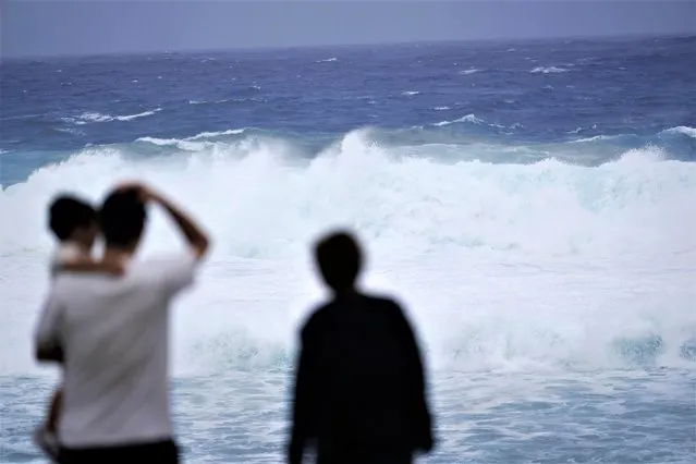 Family members watch waves affected by a severe weather system in Itoman, southern Japan, Wednesday, May 31, 2023, as Typhoon Mawar moves towards the Okinawa islands. (Photo by Hiro Komae/AP Photo)