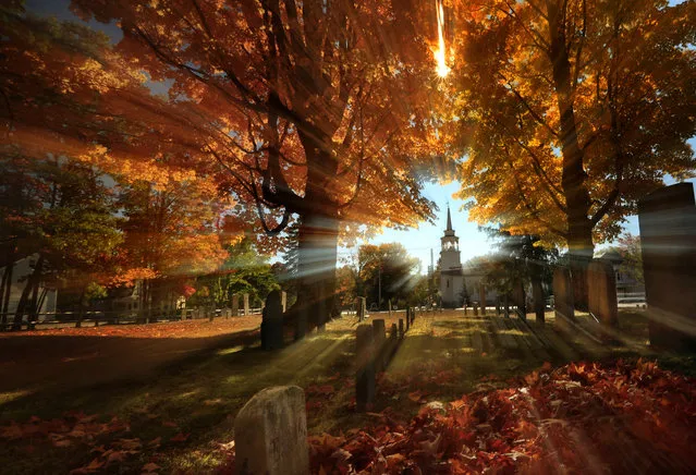 In this photo taken with a slow shutter speed, autumn's colors peak on hardwood trees in a cemetery near the Congregational Church, Monday, October 10, 2016, in Cumberland, Maine. (Photo by Robert F. Bukaty/AP Photo)