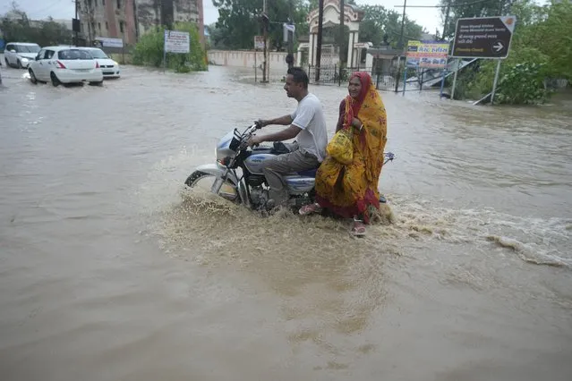 A couple ride a motorcycle through a flooded street following heavy winds and incessant rains after landfall of cyclone Biparjoy at Mandvi in Kutch district of Western Indian state of Gujarat, Friday, June 16, 2023. Cyclone Biparjoy knocked out power and threw shipping containers into the sea in western India on Friday before aiming its lashing winds and rain at part of Pakistan that suffered devastating floods last year. (Photo by Ajit Solanki/AP Photo)