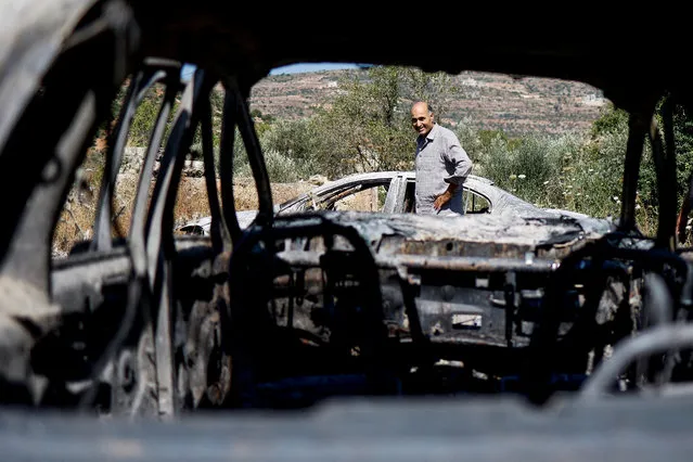 A Palestinian man checks burned vehicles after an attack by Israeli settlers near Ramallah in the Israeli-occupied West Bank on June 21, 2023. (Photo by Ammar Awad/Reuters)