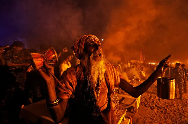 A Sadhu or a Hindu holy man plays a damru, a small two headed drum, as he offers prayers at the banks of the Ganga river on the occasion of the annual Hindu festival of “Karthik Purnima” or full moon night, in Allahabad, India, November 14, 2016. (Photo by Jitendra Prakash/Reuters)