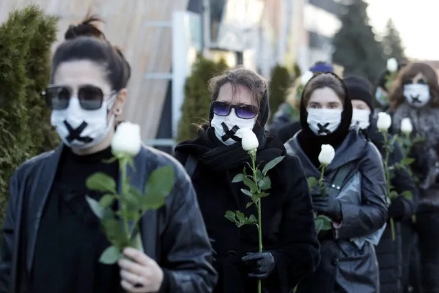 Women wearing black clothing and tape crossed over their mouths hold white roses as they march on March 2, 2021, in Minsk, during a demonstration against the conviction of a doctor and a journalist over the disclosure of medical records of a protester who died after being detained at one of the post-election rallies that swept Belarus last year. Journalist Katerina Borisevich, 36, was sentenced to six months in jail while doctor Artyom Sorokin, 37, was released from custody, but will have to serve two years in prison if he is found to have committed any crimes within a one-year period. (Photo by AFP Photo/Stringer)