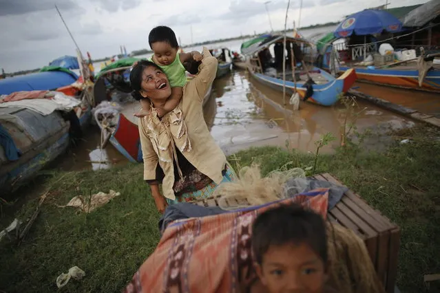 An ethnic Cham Muslim woman plays with her child on banks of Mekong river in Phnom Penh July 27, 2013. About 100 ethnic Cham families, made up of nomads and fishermen without houses or land who arrived at the Cambodian capital in search of better lives, live on their small boats on a peninsula where the Mekong and Tonle Sap rivers meet, just opposite the city's centre. The community has been forced to move several times from their locations in Phnom Penh as the land becomes more valuable. They fear that their current home, just behind a new luxurious hotel under construction at the Chroy Changva district is only temporary and that they would have to move again soon. (Photo by Damir Sagolj/Reuters)