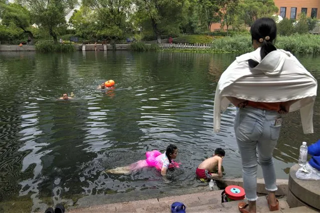 Residents cool off from an unseasonably hot day at an urban waterway in Beijing, Monday, July 3, 2023. (Photo by Andy Wong/AP Photo)