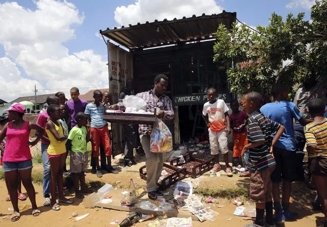 A foreign shop owner (C) collects what remains from his shop after it was looted during service delivery protests in Mohlakeng, west of Johannesburg, February 4, 2015. (Photo by Siphiwe Sibeko/Reuters)