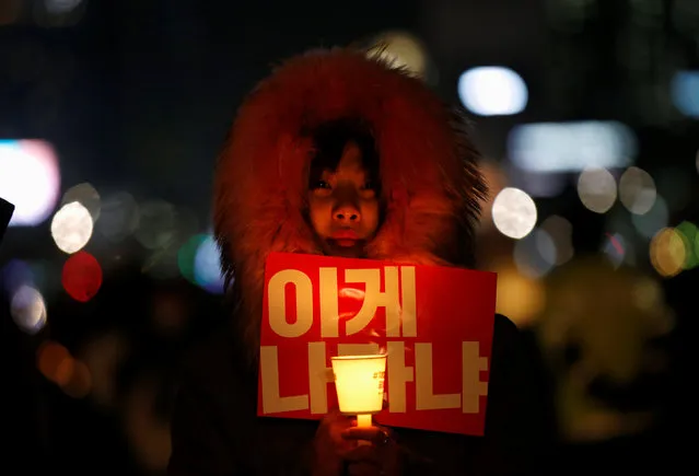 A woman holds a candle light and a slogan at a protest calling South Korean President Park Geun-hye to step down in Seoul, South Korea, November 25, 2016. The slogan reads, “Is this called a country?”. (Photo by Kim Hong-Ji/Reuters)