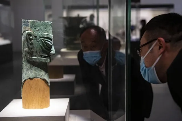 Visitors look at an ancient bronze figure statue unearthed from the Sanxingdui Ruins at the National Museum of China on March 26, 2021 in Beijing, China. The shock of hundreds of more than 3,000-year-old cultural relics newly excavated from the Sanxingdui Ruins site in SW China's Sichuan continues across China. Some stunning discoveries from the Sanxingdui Ruins preserved at the National Museum of China has drawn a number of visitors. (Photo by Hou Yu/China News Service via Getty Images)