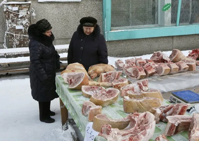 Women look at pork, transported from a local private farm in the village of Bolshaya Murta, for sale at a street market in Krasnoyarsk, Siberia, Russia, January 12, 2016. (Photo by Ilya Naymushin/Reuters)