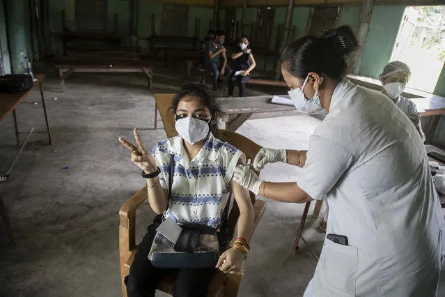 An Indian woman getting vaccinated with a dose of COVAXIN against the coronavirus gestures to camera in Gauhati, Assam, India, Monday, May 10, 2021. (Photo by Anupam Nath/AP Photo)