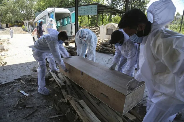 Health workers and relatives carry the body of a COVID-19 victim for cremation in Jammu, India, Monday, May 24, 2021. India crossed another grim milestone Monday of more than 300,000 people lost to the coronavirus as a devastating surge of infections appeared to be easing in big cities but was swamping the poorer countryside. (Photo by Channi Anand/AP Photo)