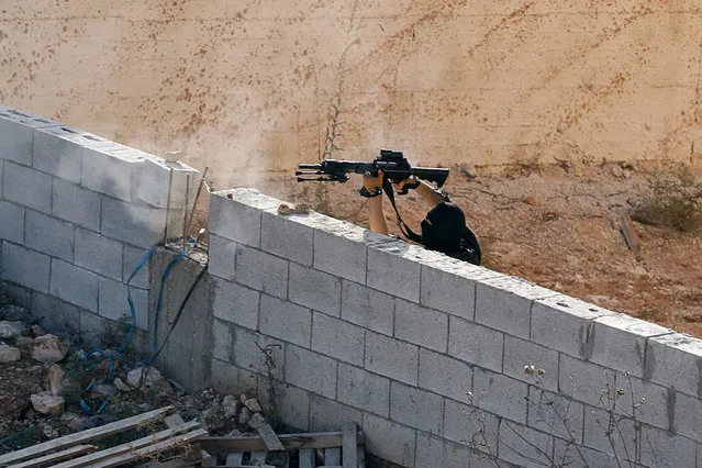 A Palestinian militant shoots at Israeli forces as they take up position near a house where a Palestinian militant is hiding during a raid near Tubas in the Israeli-occupied West Bank on September 1, 2023. (Photo by Raneen Sawafta/Reuters)