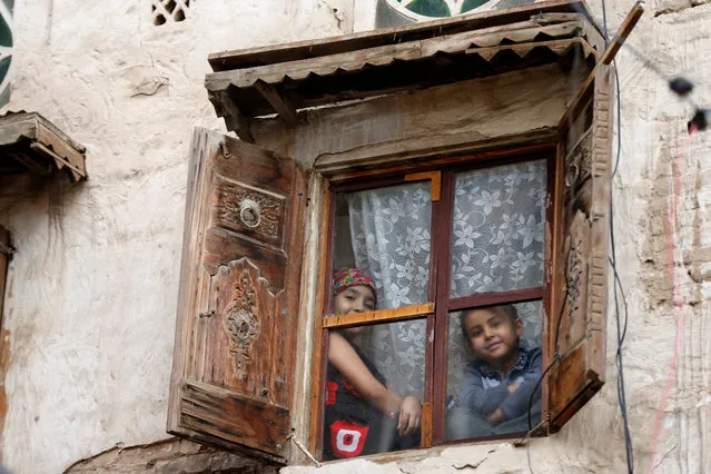 Children look from behind a window of a house in the old quarter of Sanaa, Yemen on August 14, 2018. (Photo by Khaled Abdullah/Reuters)