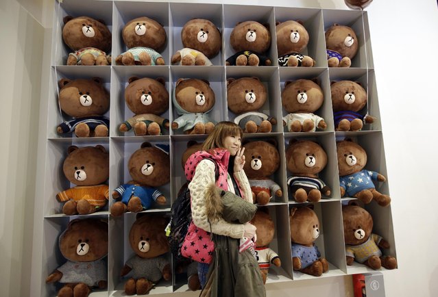 In this March 16, 2015 photo, a tourist from Hong Kong poses for her souvenir photo in front of Line’s character Brown bear at the Line Friends flagship shop in Seoul, South Korea. For smartphone users in Asia where most of Line’s 181 million monthly users are located, the characters are as familiar as Hello Kitty or Disney’s animated stars. They are not well known in America or Europe but owner Line Corp. hopes to change that. (Photo by Lee Jin-man/AP Photo)